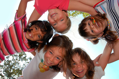 Five kids standing in a circle, linking arms, looking down at the camera.