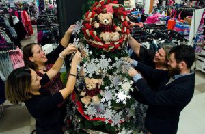 Four people decorate a Christmas tree inside a Sears.