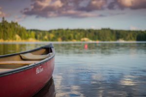 The front half of a canoe is visible, floating on a lake.