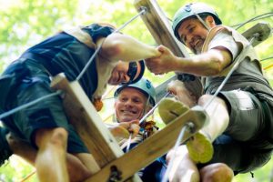 Three men on a wooden platform, doing some kind of outdoor activity. 