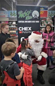 A person dressed as Santa hugging a child, surrounded by other children.