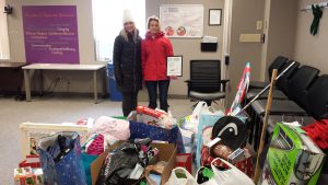 Two adults standing behind a pile of donated items.