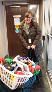 A woman pushing a cart carrying two baskets of donated items.