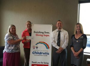 Four foundation members standing near a KHCF sign; two of them hold up a cheque received from a credit unions support.