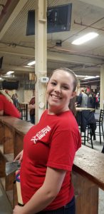 A woman wearing a red Axe Club shirt, smiling and looking at the camera.