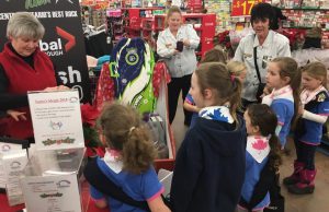 A group of young girls speaking to volunteers at the give-a-gift board in Walmart 