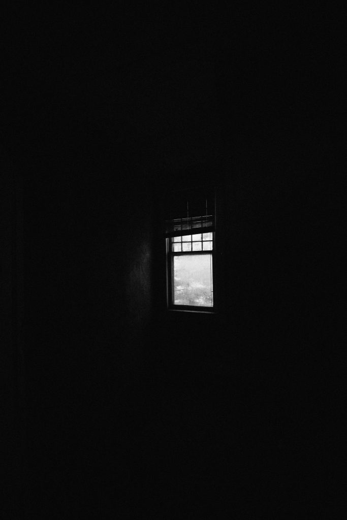 A pitch-dark room with a small window emitting light.