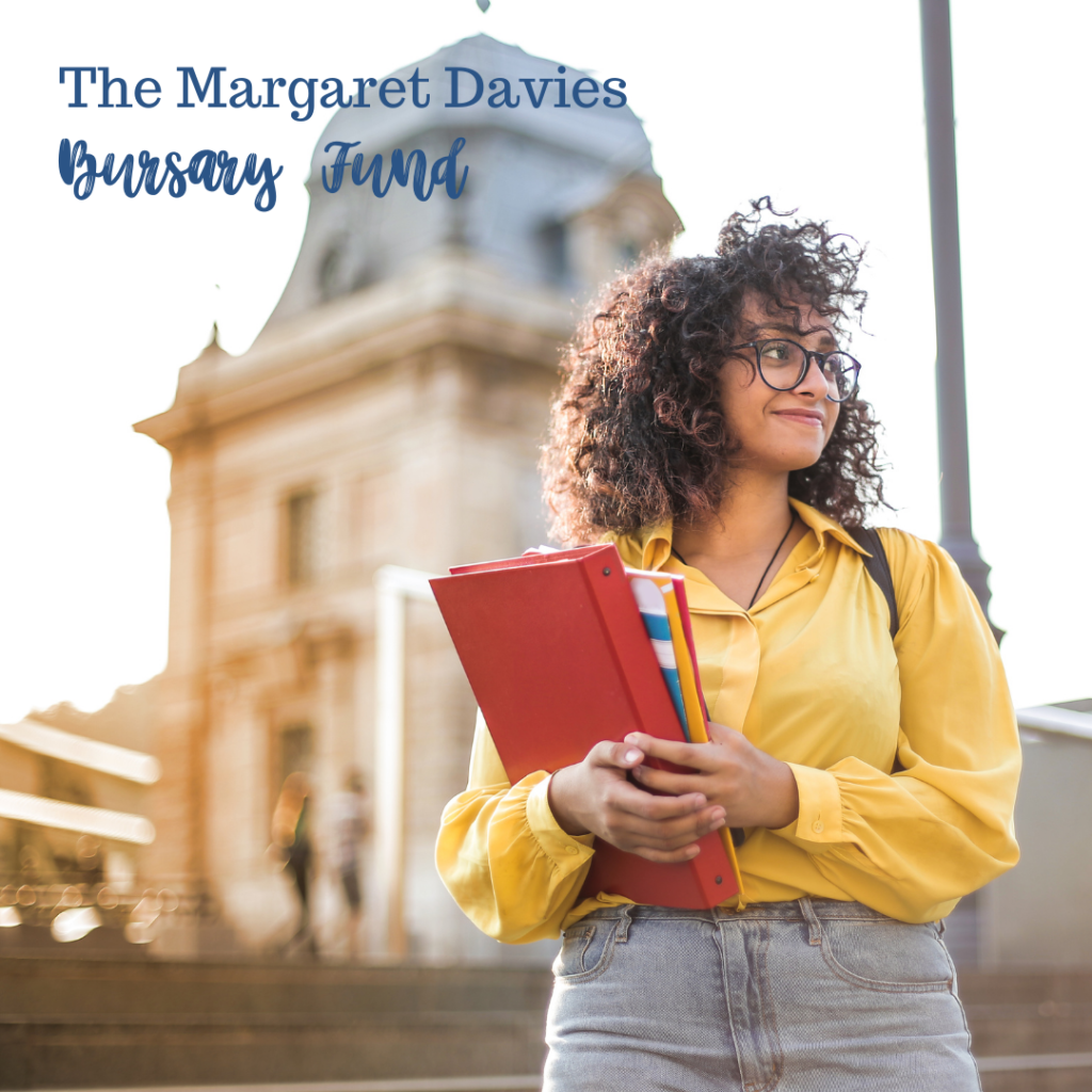 A photo of a girl holding a book and looking off into the distance, with the words The Margaret Davies Bursary Fund in the left upper corner